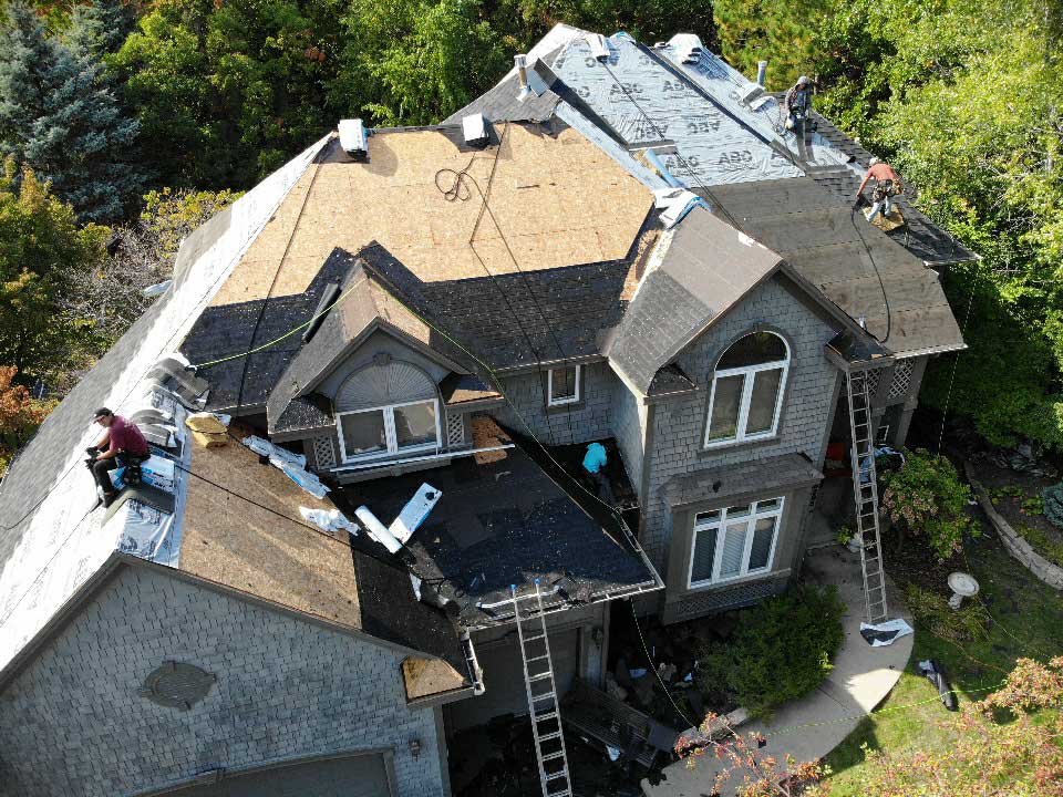 Drone photo of an in progress roofing job from the side, 3 workers