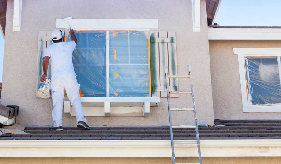 Patriot Homes Painting Professionals Man painting the sides of the window on top of the roof