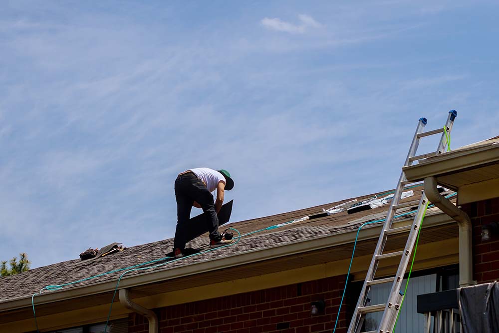 A Construction worker working on a roof and installing new shingles