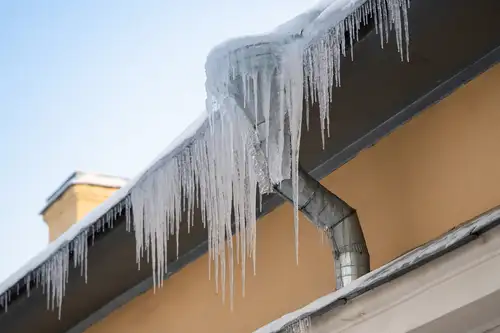 Icicles and Ice Dam forming on top of the gutters because of snowy roof
